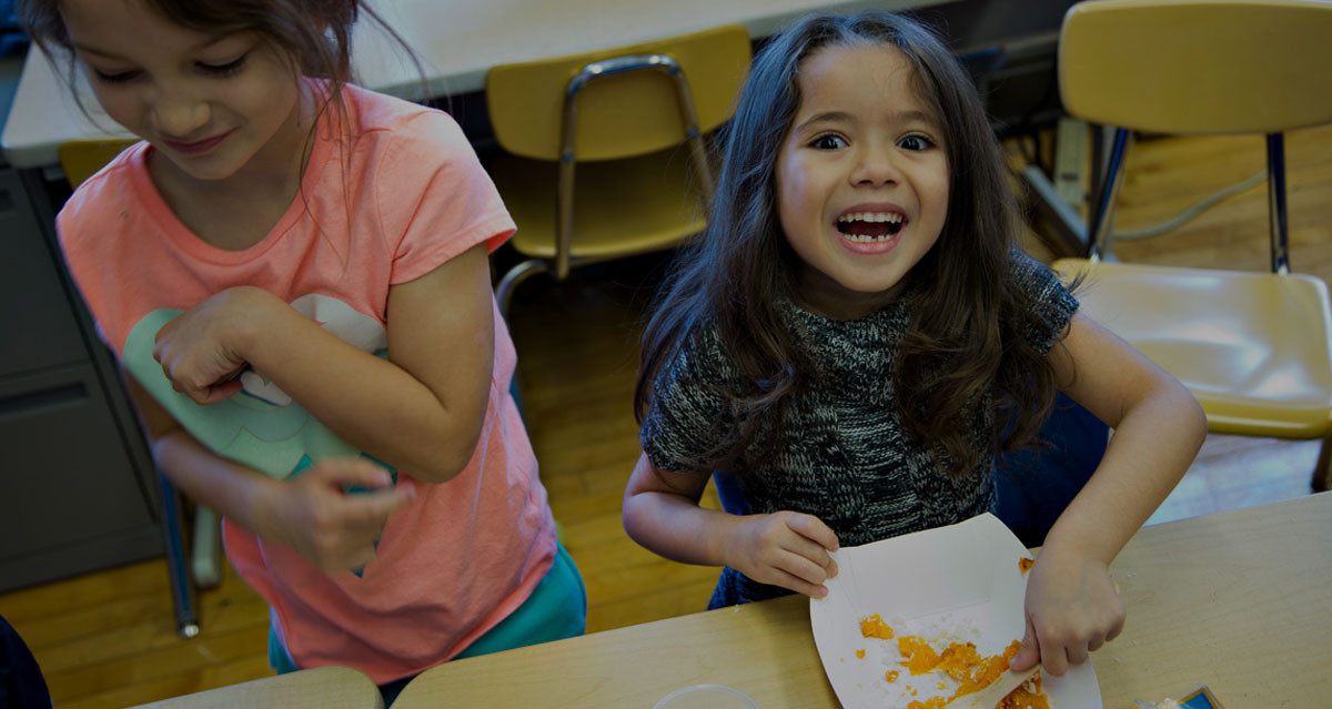 girls eating at desks in classroom