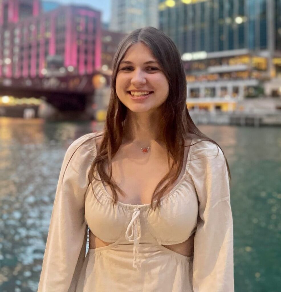 Pilot Light Intern Ava Hampe, smiles at the camera with the Chicago River in the background